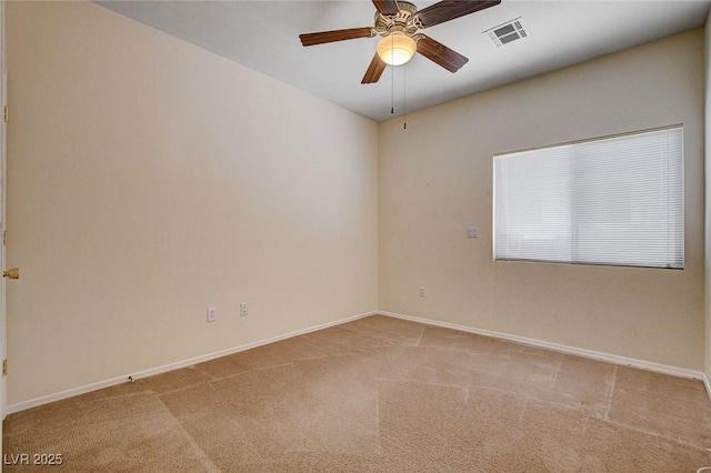 carpeted spare room with baseboards, a ceiling fan, and visible vents