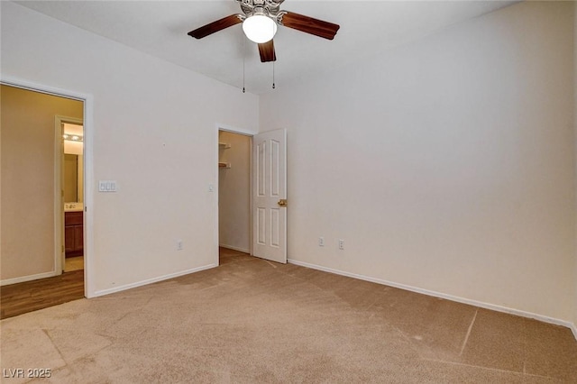 unfurnished bedroom featuring baseboards, carpet flooring, a walk in closet, and ceiling fan