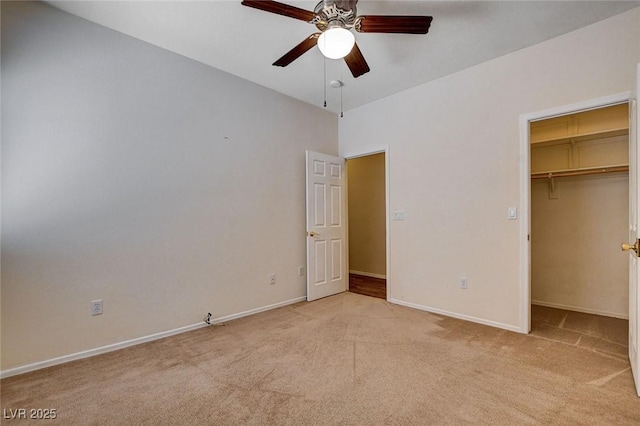 unfurnished bedroom featuring baseboards, a walk in closet, and light carpet