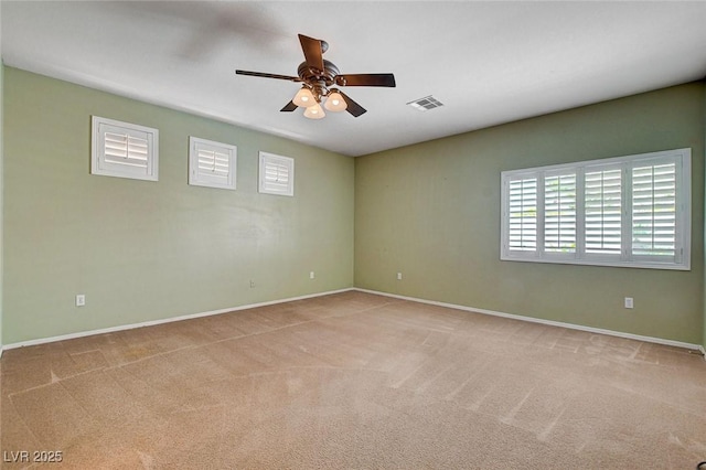 empty room with baseboards, ceiling fan, visible vents, and a wealth of natural light