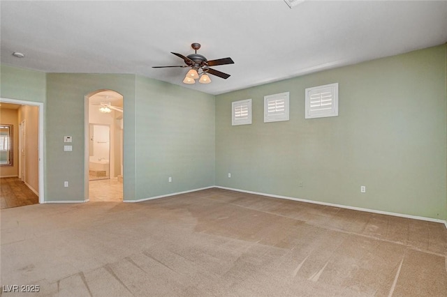 spare room featuring carpet floors, arched walkways, ceiling fan, and a wealth of natural light