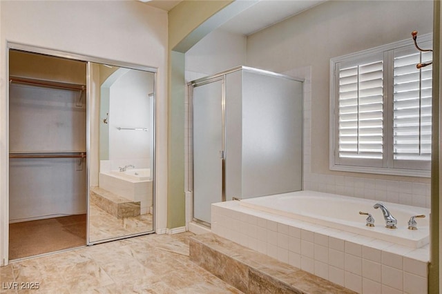 bathroom featuring a shower stall, a bath, and a spacious closet