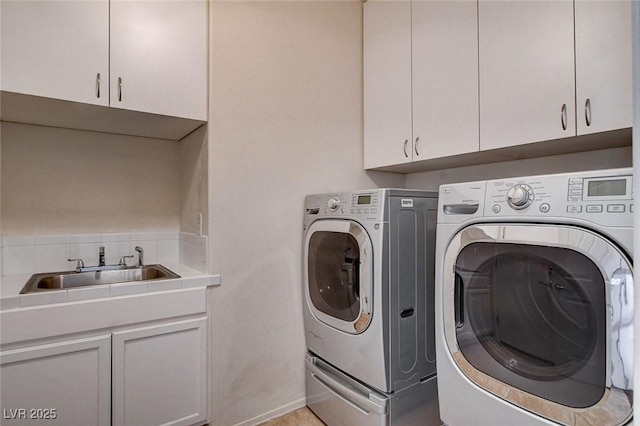 clothes washing area with separate washer and dryer, a sink, cabinet space, and baseboards