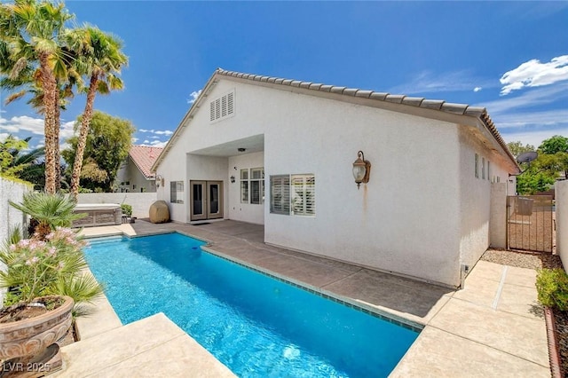 rear view of house with a patio, a fenced backyard, stucco siding, french doors, and a fenced in pool