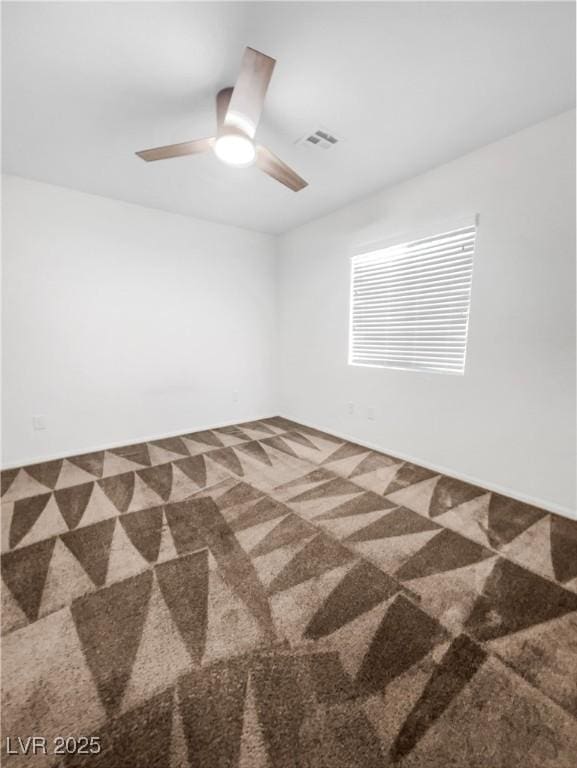 carpeted spare room with visible vents and a ceiling fan