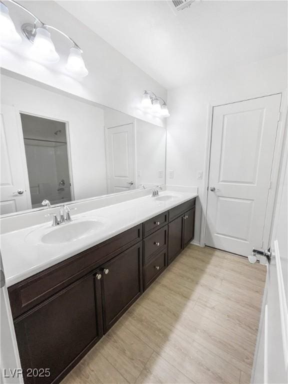 bathroom with double vanity, a sink, and wood finished floors
