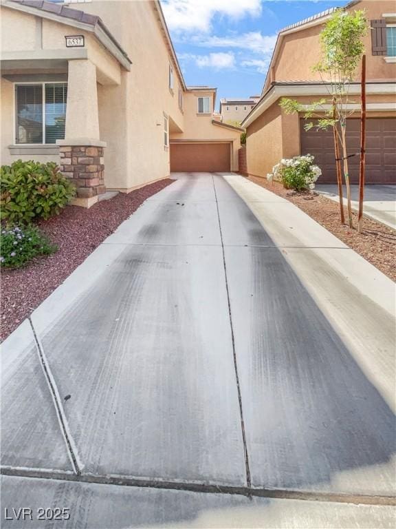 view of property exterior with a garage, stucco siding, driveway, and stone siding
