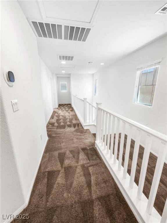 corridor with carpet flooring, visible vents, and an upstairs landing