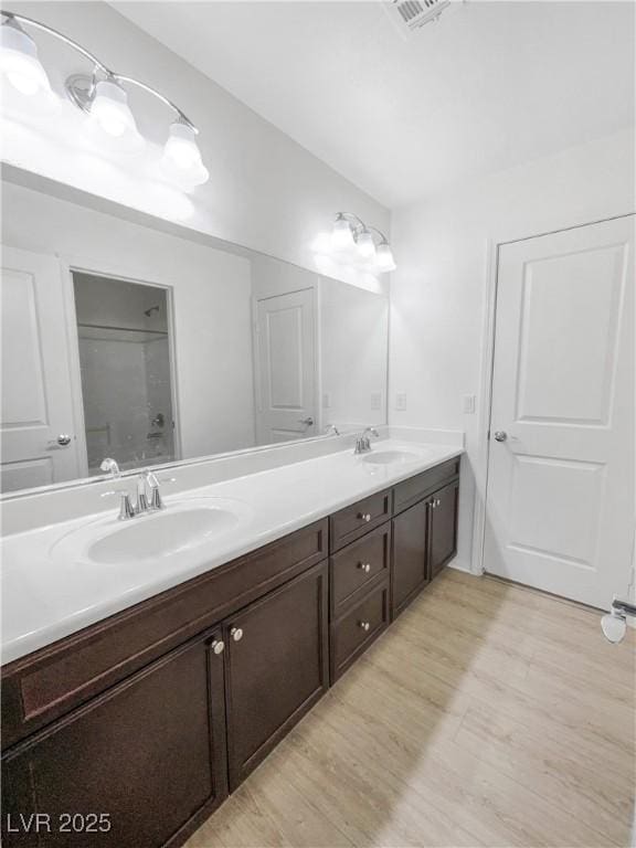 full bathroom featuring double vanity, a sink, and wood finished floors