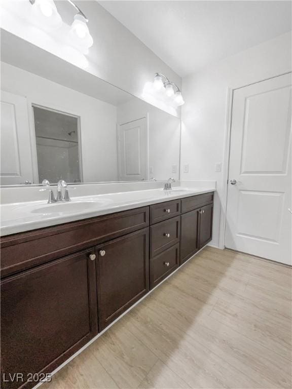 bathroom with double vanity, a sink, and wood finished floors