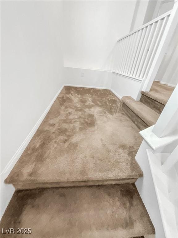 staircase featuring baseboards and carpet