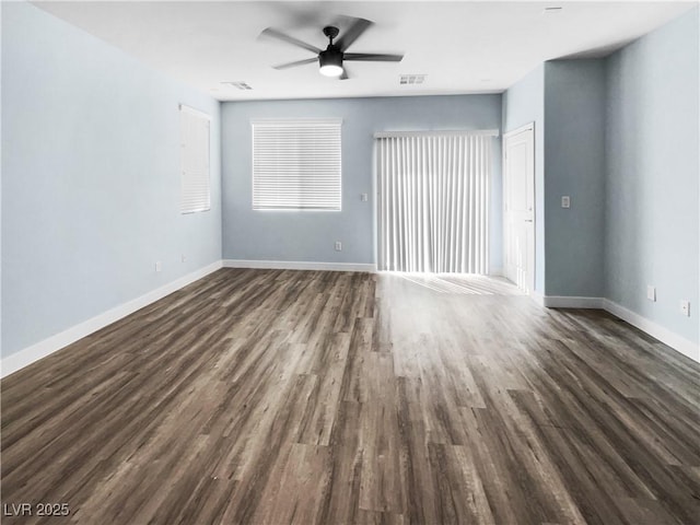 empty room featuring visible vents, dark wood-type flooring, baseboards, and ceiling fan