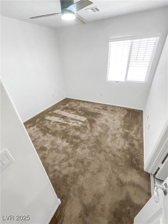 empty room with carpet floors, a ceiling fan, and visible vents