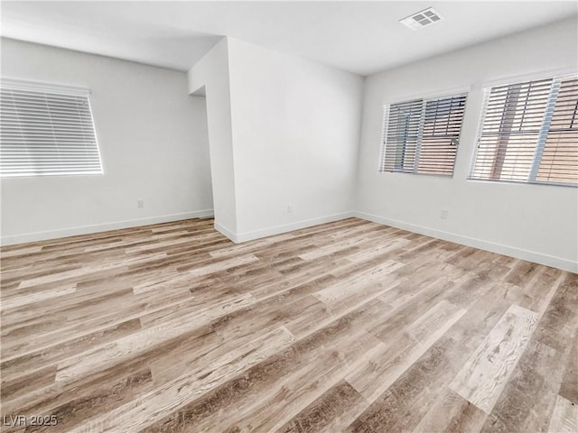spare room featuring visible vents, light wood-style flooring, and baseboards