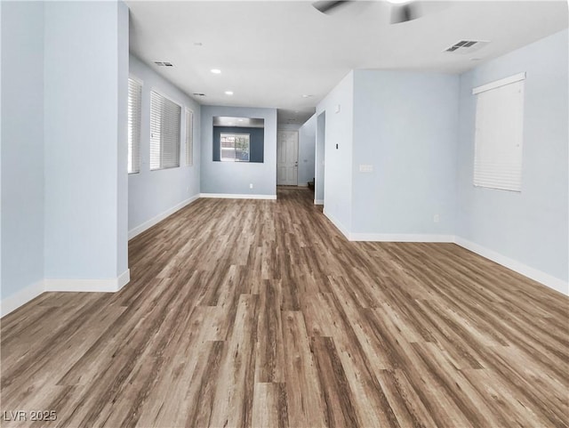 spare room with baseboards, a ceiling fan, wood finished floors, and visible vents