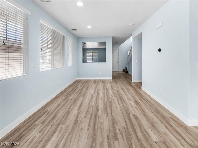 spare room with light wood finished floors, stairs, recessed lighting, baseboards, and visible vents