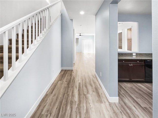 hallway with a healthy amount of sunlight, stairs, and light wood-style flooring