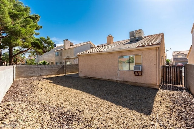 2805 Rungsted St, Las Vegas, NV 89142 - back of house with a tiled roof, central AC unit, a fenced backyard, and a chimney