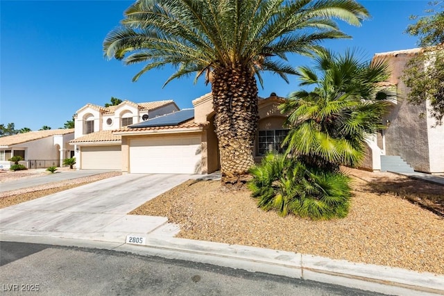 2805 Rungsted St, Las Vegas, NV 89142 - mediterranean / spanish home with concrete driveway, an attached garage, roof mounted solar panels, and stucco siding