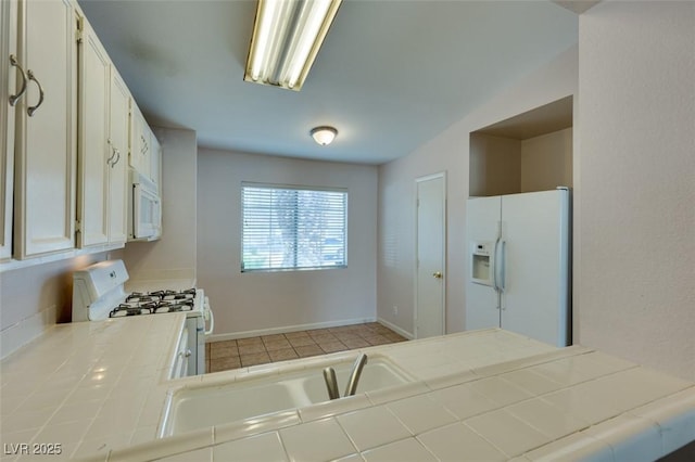 2805 Rungsted St, Las Vegas, NV 89142 - kitchen with white appliances, baseboards, tile countertops, white cabinets, and light tile patterned floors