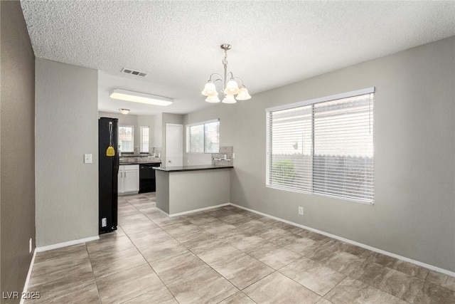 6428 Yarmouth Dr, Las Vegas, NV 89108 - kitchen with a peninsula, dark countertops, black appliances, a textured ceiling, and a notable chandelier