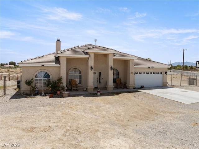 view of front of home with fence, a chimney, driveway, and stucco siding