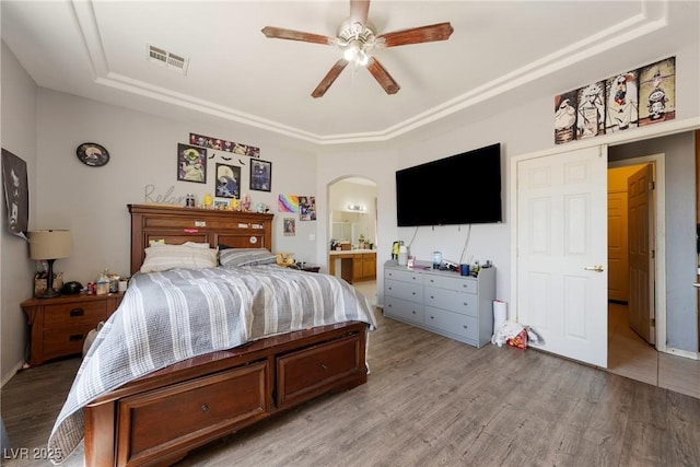 bedroom featuring a tray ceiling, visible vents, and light wood finished floors