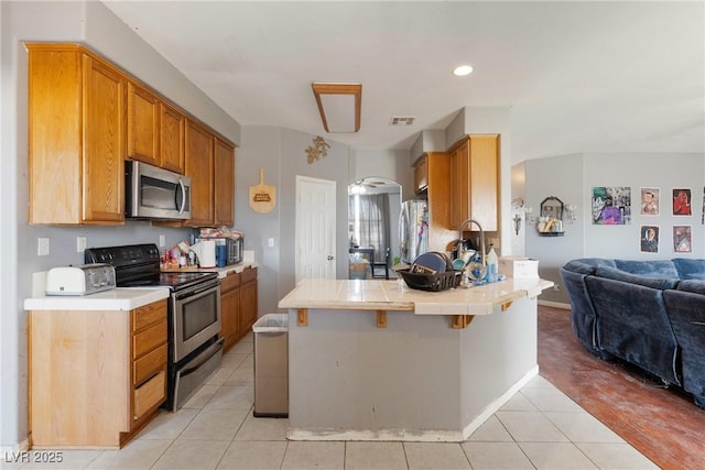 kitchen featuring visible vents, light tile patterned floors, a peninsula, open floor plan, and stainless steel appliances