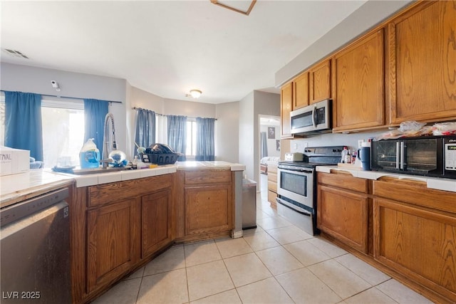 kitchen with visible vents, light tile patterned floors, brown cabinets, and stainless steel appliances