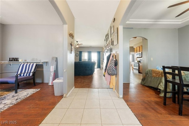 corridor with arched walkways, tile patterned floors, and baseboards