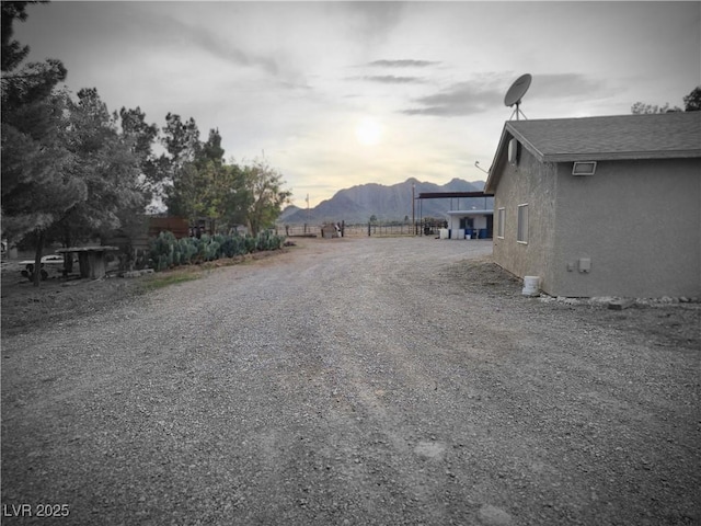 view of street with a mountain view and gravel driveway