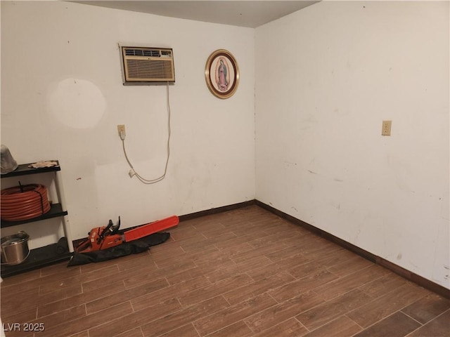 unfurnished room with baseboards, dark wood finished floors, and a wall unit AC