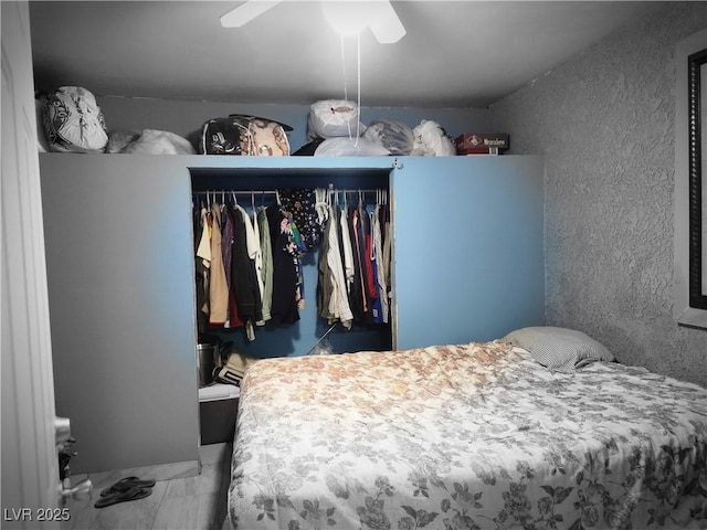 bedroom featuring a textured wall, ceiling fan, marble finish floor, and a closet