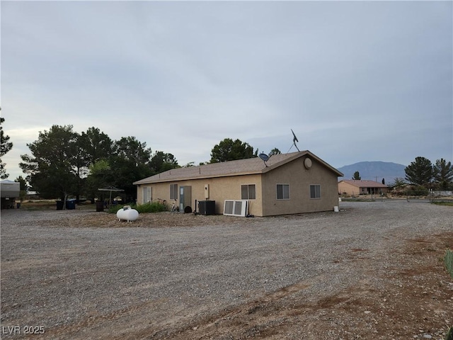 view of front of home with cooling unit, a mountain view, and stucco siding