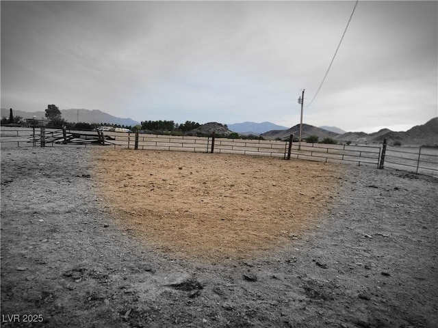 view of yard featuring an enclosed area, a mountain view, a rural view, and fence