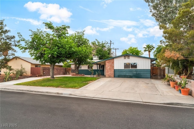 ranch-style home featuring fence, a front yard, brick siding, board and batten siding, and concrete driveway