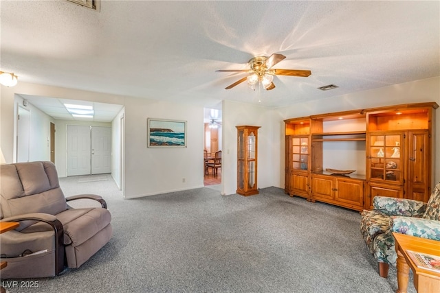 living room featuring a textured ceiling, ceiling fan, visible vents, and light carpet