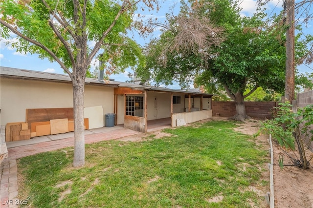 back of property featuring fence, stucco siding, a lawn, and a patio area