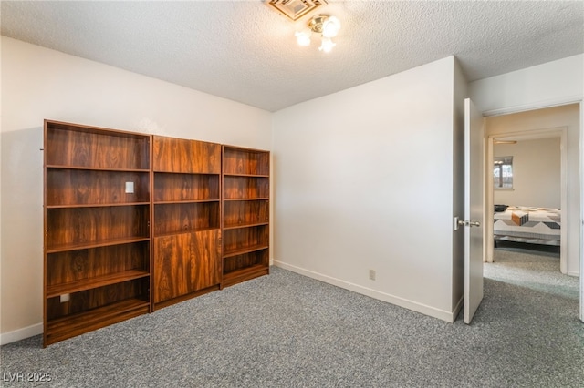 unfurnished bedroom with carpet floors, a textured ceiling, baseboards, and visible vents