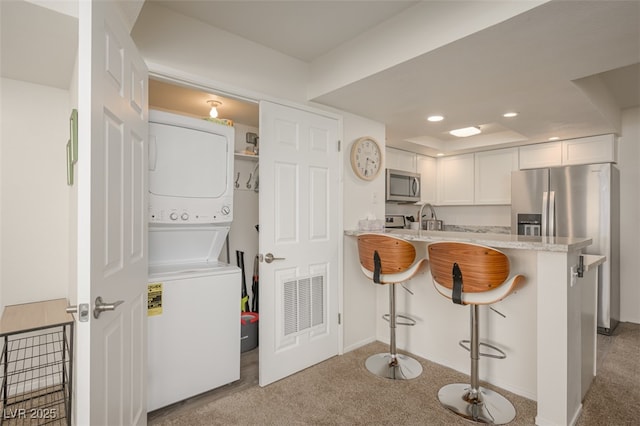 clothes washing area with laundry area, light colored carpet, recessed lighting, baseboards, and stacked washer and clothes dryer