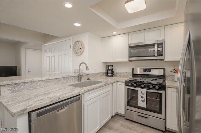 kitchen with white cabinets, a sink, stainless steel appliances, recessed lighting, and a peninsula
