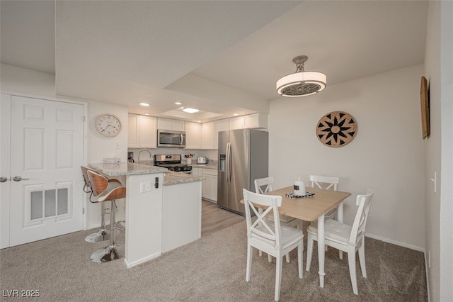 kitchen with visible vents, a peninsula, a breakfast bar area, white cabinets, and stainless steel appliances