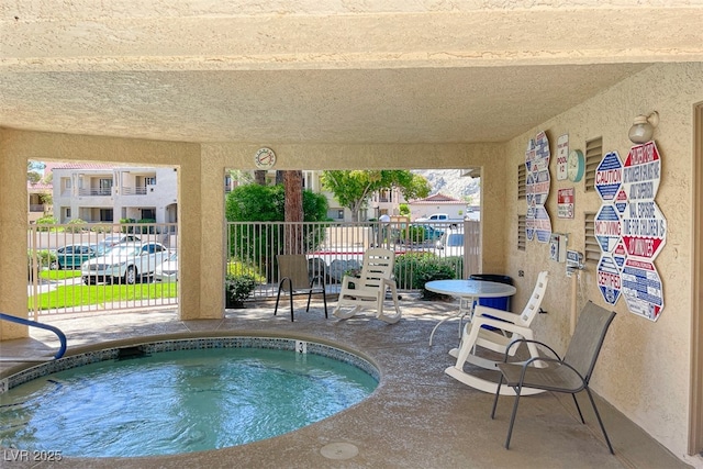 view of swimming pool with a patio, a community hot tub, and fence