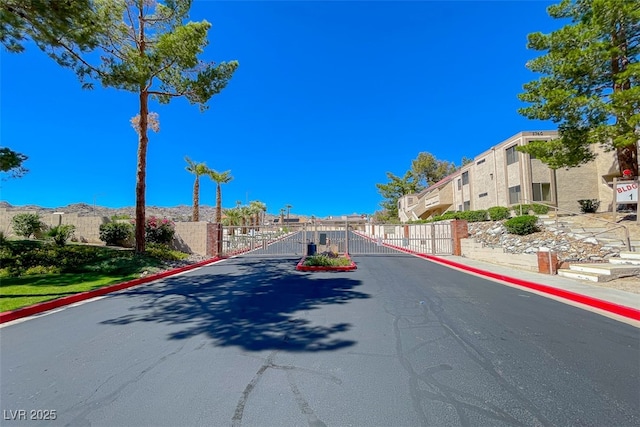 view of road with a residential view, a gated entry, a gate, and curbs