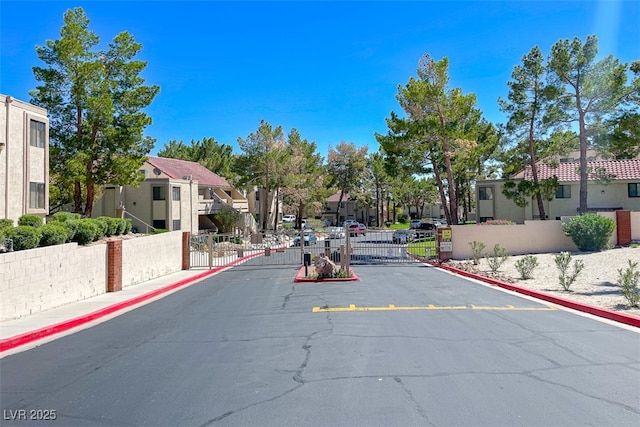 view of street featuring a residential view, sidewalks, a gated entry, curbs, and a gate