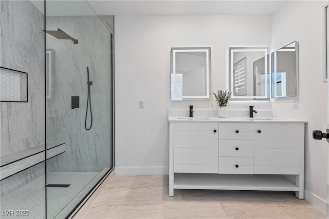 bathroom with a sink, baseboards, double vanity, and a marble finish shower