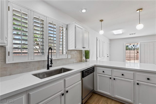 kitchen with backsplash, visible vents, stainless steel dishwasher, a sink, and light countertops