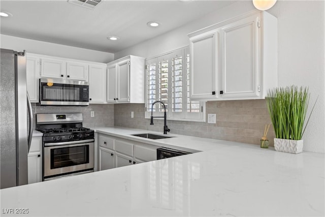 kitchen featuring backsplash, stainless steel appliances, white cabinetry, and a sink