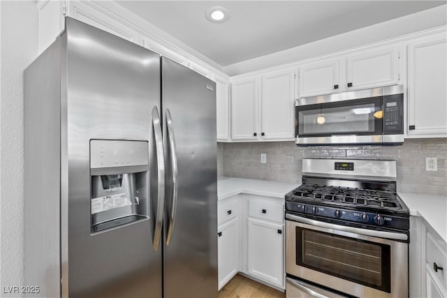 kitchen featuring light countertops, decorative backsplash, white cabinets, and stainless steel appliances