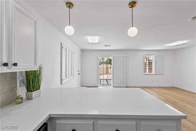 kitchen with white cabinets, light wood-style flooring, a peninsula, open floor plan, and decorative backsplash